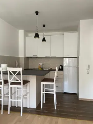 a kitchen with white cabinets and a table and chairs at Home Away Apartment in Podgorica