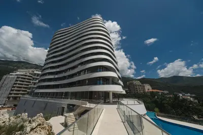 a tall building with a pool in front of it at La barca apartments in Becici