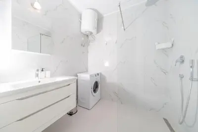 a white bathroom with a sink and a washing machine at La barca apartments in Becici
