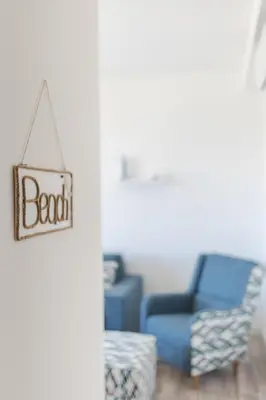 a living room with a blue chair and a sign that reads beach at La barca apartments in Becici