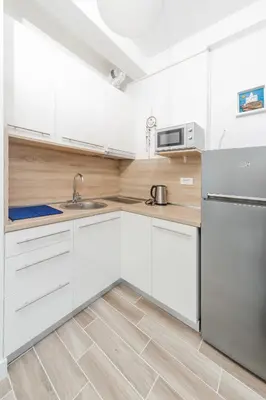 a white kitchen with white cabinets and a sink at La barca apartments in Becici