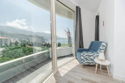 a room with a blue chair and a large window at La barca apartments in Becici