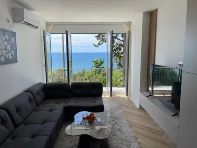 a living room with a couch and a view of the ocean at Pine forest apartment in Ulcinj
