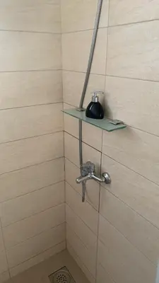 a shower with a glass shelf on the wall at LamijaApartmani in Sutomore