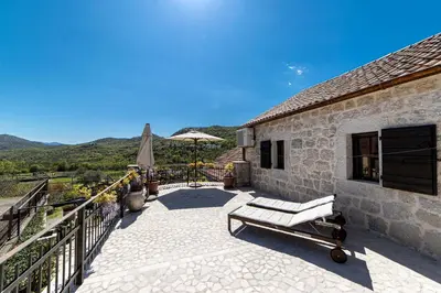 a patio with a bench and an umbrella on a building at Stone Villa Oblun in Briđe