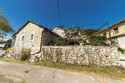 a stone house behind a stone retaining wall at Stone Villa Oblun in Briđe