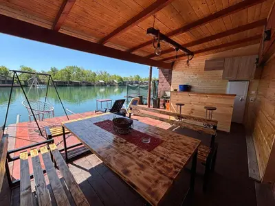 a wooden deck with a table and chairs on a boat at Kućica Vukčević Ada Bojana in Ulcinj