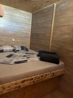 a bed in a room with a wooden wall at Kućica Vukčević Ada Bojana in Ulcinj