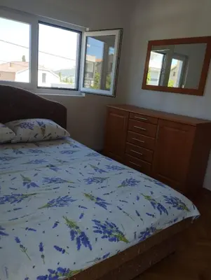 a bedroom with a bed and a dresser and two windows at Vila Šeki in Bar