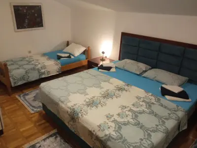 a bedroom with two beds with blue sheets and a blue headboard at HeArt of Old Town Guesthouse in Podgorica
