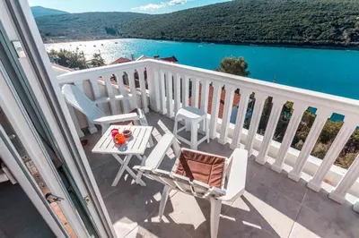 a balcony with chairs and a table and a view of the water at Sea Oasis Apartments - Milosevic in Kotor