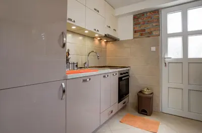 a kitchen with white cabinets and a sink and a door at Sea Oasis Apartments - Milosevic in Kotor