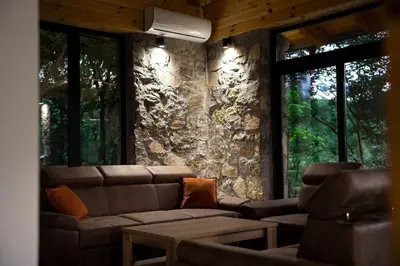 a living room with a couch and a stone wall at Rijeka Zeta, Podgorica in Podgorica