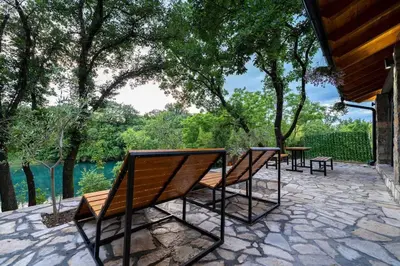 a group of benches sitting on a patio with trees at Rijeka Zeta, Podgorica in Podgorica