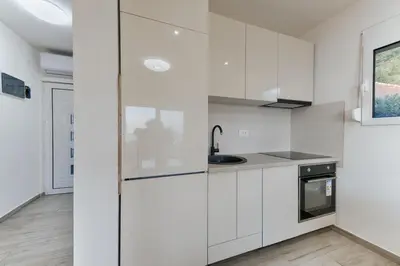 a kitchen with white cabinets and a sink at Vila HELENA in Dobra Voda