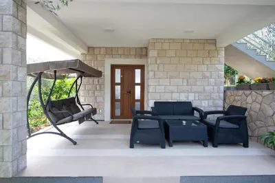 a patio with chairs and a table and a swing at Rustic Olive House in Ulcinj