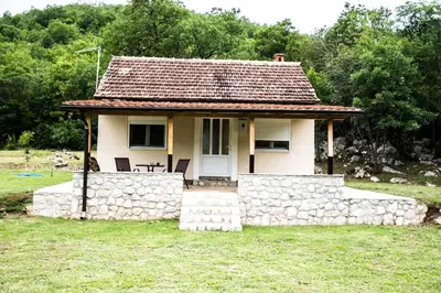 a small white house with a stone wall at Village house Katarina in Cetinje
