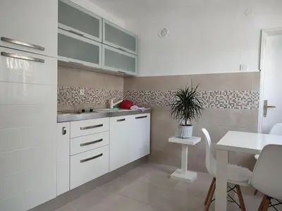 a kitchen with white cabinets and a table and a plant at B&B Ana in Virpazar