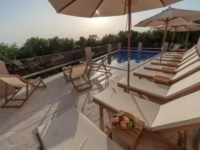 a pool with chairs and tables and an umbrella at Hotel Diman in Dobra Voda