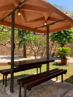 a wooden bench under a large umbrella in a park at Apartments Moskov in Kotor