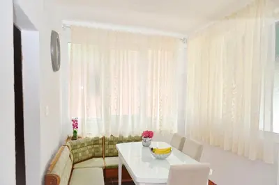 a white dining room with a white table and chairs at Apartman Stefan in Kotor