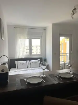 a table with two wine glasses and a couch in a room at Studio Pao in Podgorica