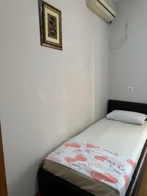 a small bedroom with a bed with a white wall at Apartments Sella in Ulcinj