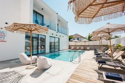 a swimming pool with chairs and umbrellas next to a building at Hotel Teuta in Ulcinj