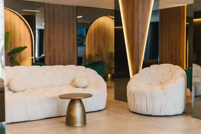 a white couch and a stool in a room at Hotel Teuta in Ulcinj