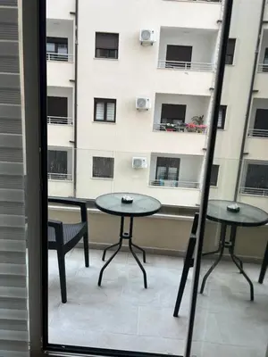 two tables and chairs on a balcony with a building at Apartman Jakov in Becici