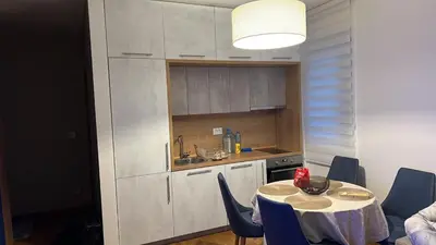 a kitchen with a table and blue chairs in a room at Apartman Jakov in Becici