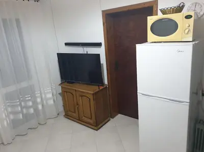 a tv sitting on top of a wooden stand next to a refrigerator at Warm & Welcoming Vele Residence in Bar