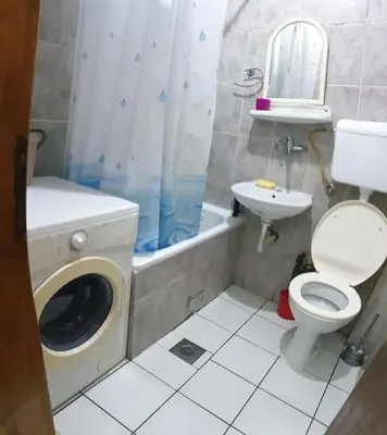 a bathroom with a washing machine and a toilet and a sink at Warm & Welcoming Vele Residence in Bar