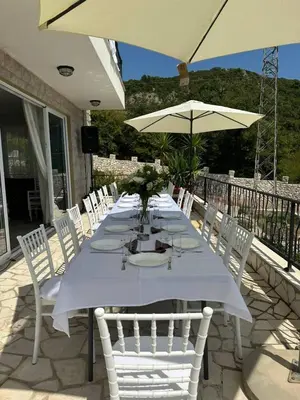 a long table with white chairs and an umbrella at Ventus Rosa Villa in Budva