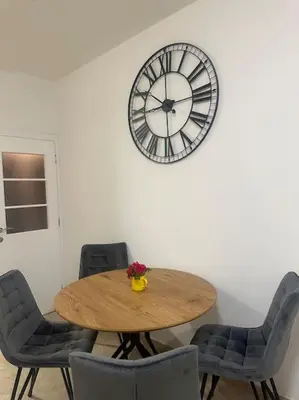 a table with chairs and a clock on a wall at Apartment Ninas in Dobrota
