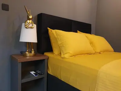 a bed with yellow pillows and a lamp on a night stand at Studio apartman Luka in Cetinje