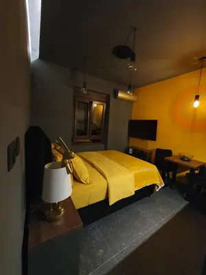 a bedroom with a yellow bed with a lamp and a table at Studio apartman Luka in Cetinje