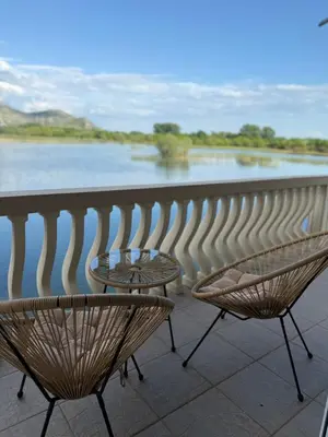 two chairs and a table on a balcony overlooking a river at Lake Skadar Paradise in Podgorica