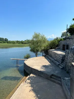 a picnic table sitting on the side of a lake at Lake Skadar Paradise in Podgorica