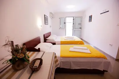 a room with two beds and a table at Apartments Baron in Sveti Stefan