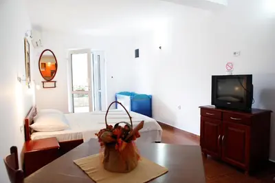 a living room with a table and a tv and a room at Apartments Baron in Sveti Stefan