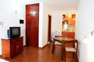 a room with a table and a tv and a kitchen at Apartments Baron in Sveti Stefan