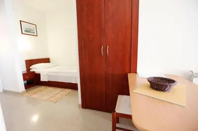 a small room with a bedroom with a bed and a cabinet at Apartments Baron in Sveti Stefan