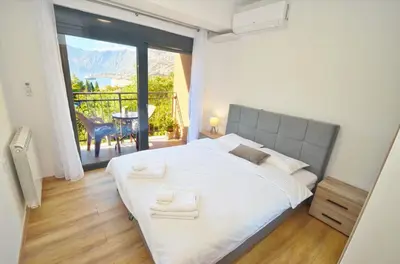 a bedroom with a large white bed and a balcony at Radgost Kotor Apartments in Kotor