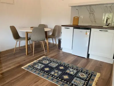 a kitchen with a table and a rug on the floor at Sabina Bungalow - Long Beach in Ulcinj