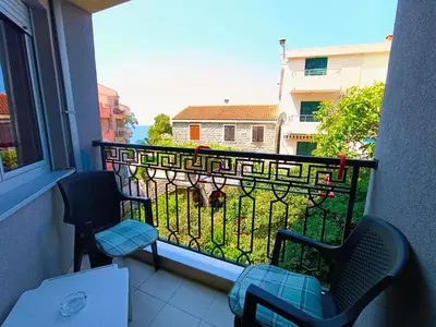 a balcony with two chairs and a view of a yard at Center Studio in Petrovac na Moru