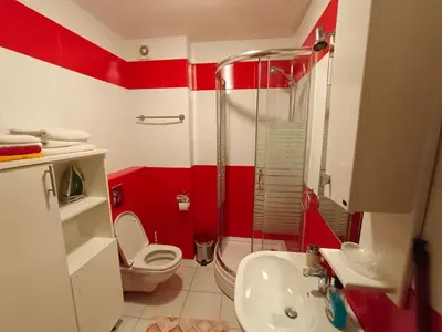 a red and white bathroom with a toilet and a sink at Center Studio in Petrovac na Moru