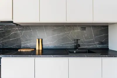 a kitchen with white cabinets and a black counter top at 2-floor penthouse with stunning views in Budva