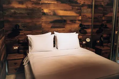 a bed with white pillows in a room with wooden walls at Carevic Resort & Villas in Budva