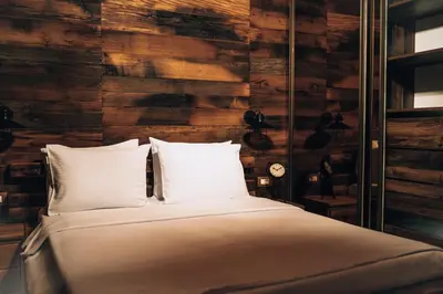 a bed with white pillows and a wooden wall at Carevic Resort & Villas in Budva